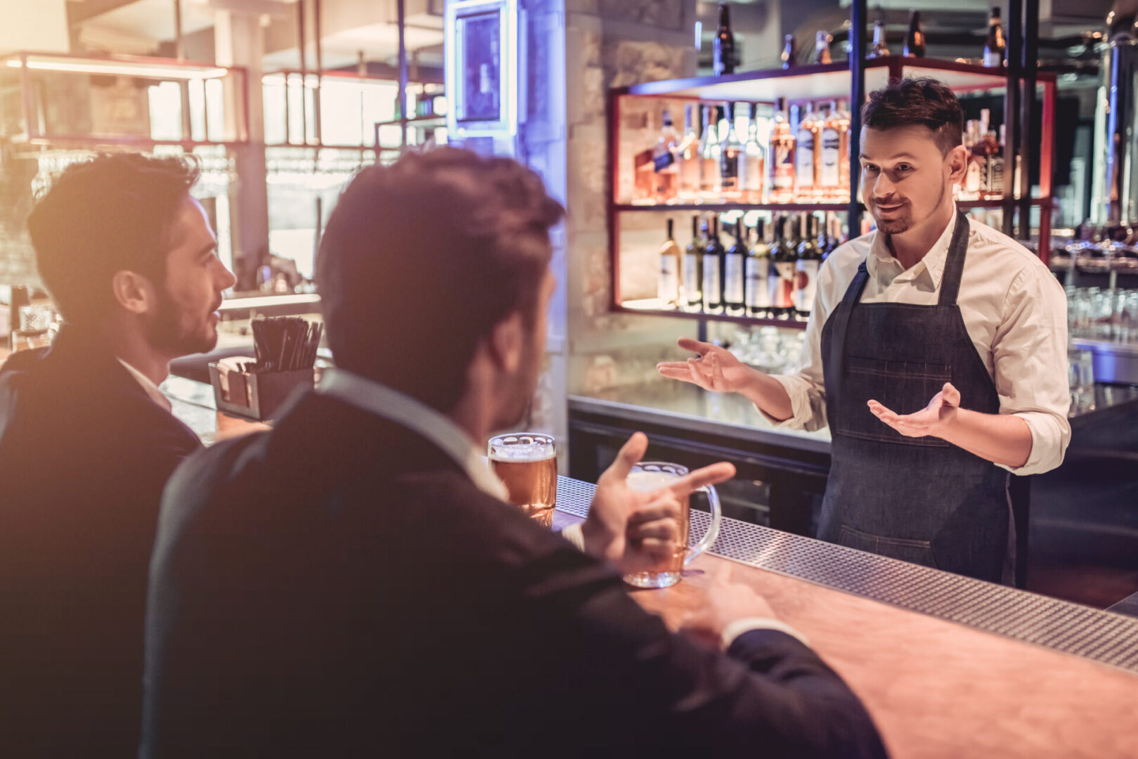 Businessmen in bar Bartender talking to two customers at bar.