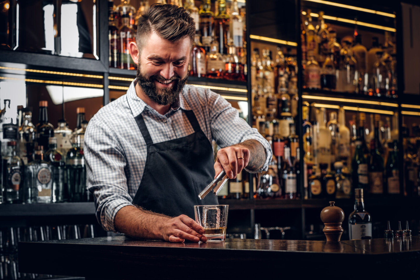 Attractive cheerful barmen is prepairing drinks Bartender preparing a drink at bar counter.